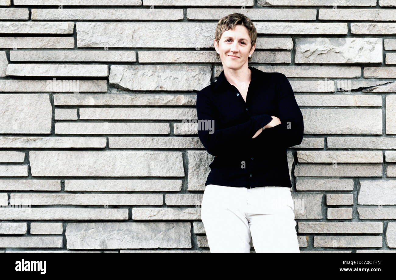 Portrait of woman with arms crossed with white stone wall Stock Photo