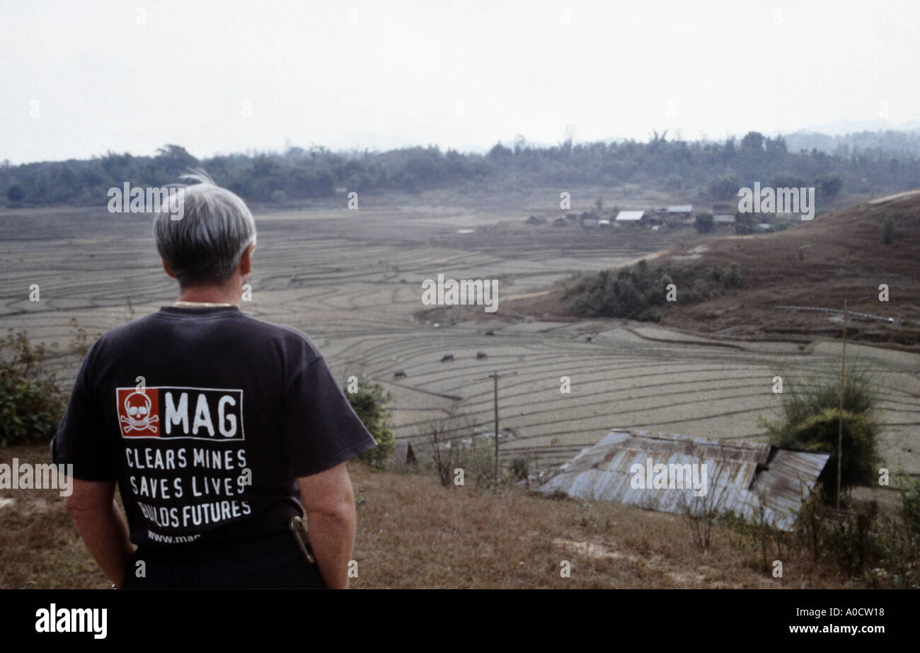 An expert in bomb and mine clearance surveys farmland surrounded by contaminated areas on the Plain of Jars in northern Laos Stock Photo