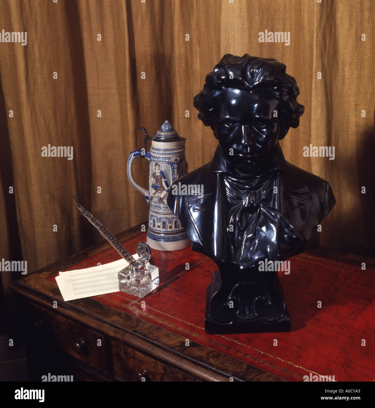 Bust of Beethoven with Tankard Quill Pen and Inkpot on Red Leather Desktop Stock Photo