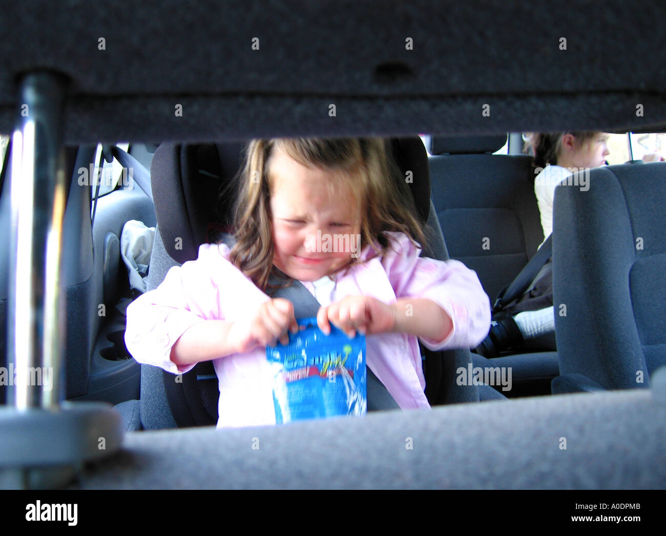 Young girl toddler having temper tantrum in car seat trying to open bag of sweets Stock Photo Alamy