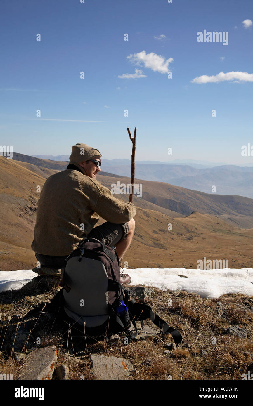 Walker sitting at snow line admiring view. Mount Aragats, Armenia, Southwest Asia Stock Photo