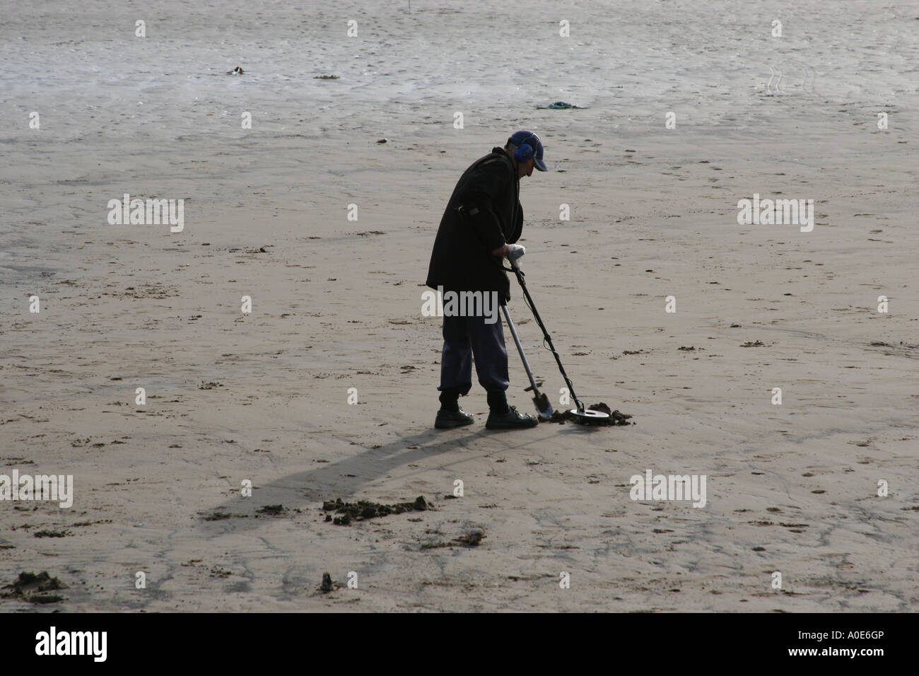 Man using metal detector on a beach searching for lost metal objects ...