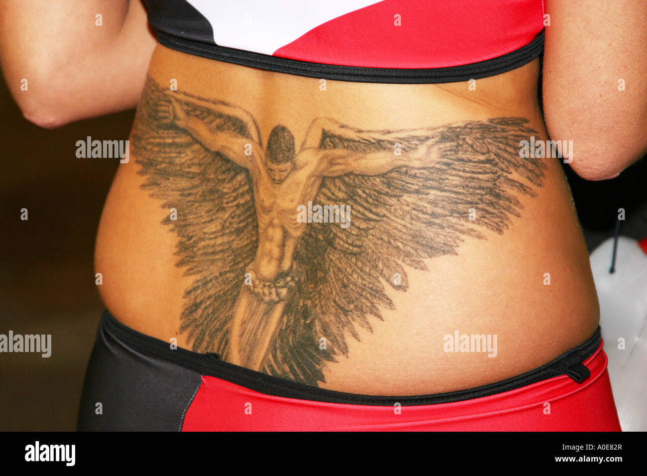 Detail of large male angel tattoo on young woman’s back. Stock Photo