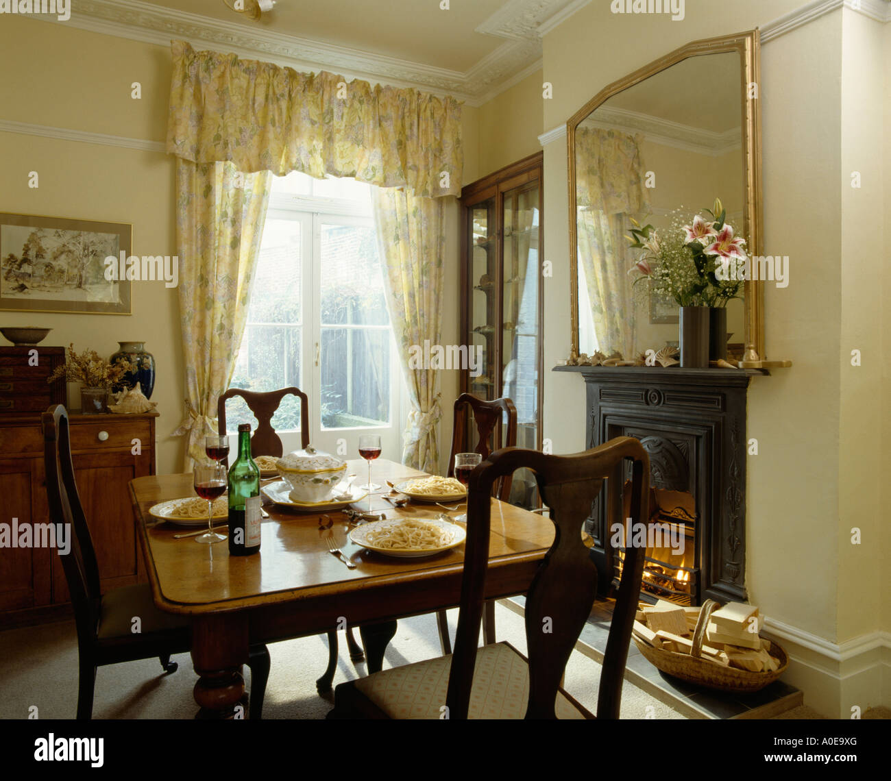 Mirror above fireplace with table settings on polished wood table Stock ...