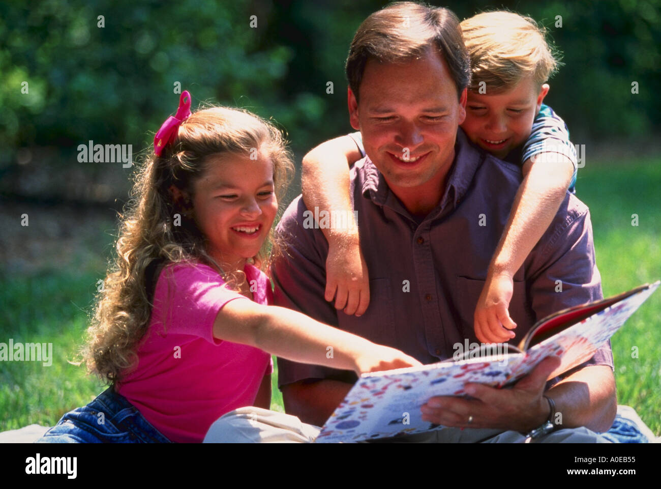 Father and kids reading in the park Stock Photo