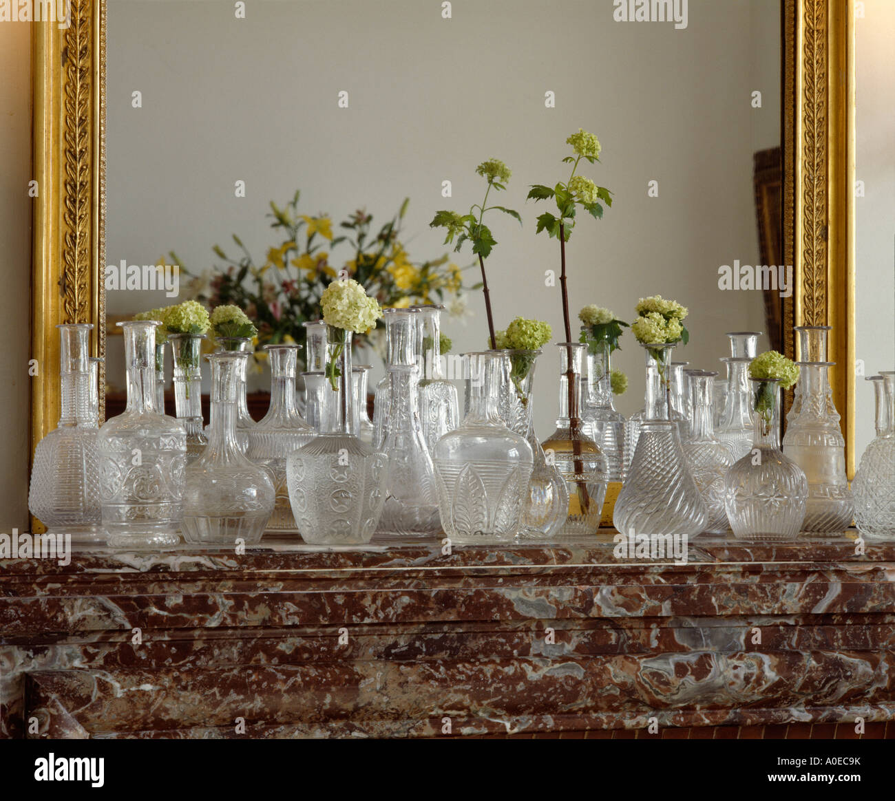 Collection of antique glass decanters in front of mirror on marble mantelpiece Stock Photo