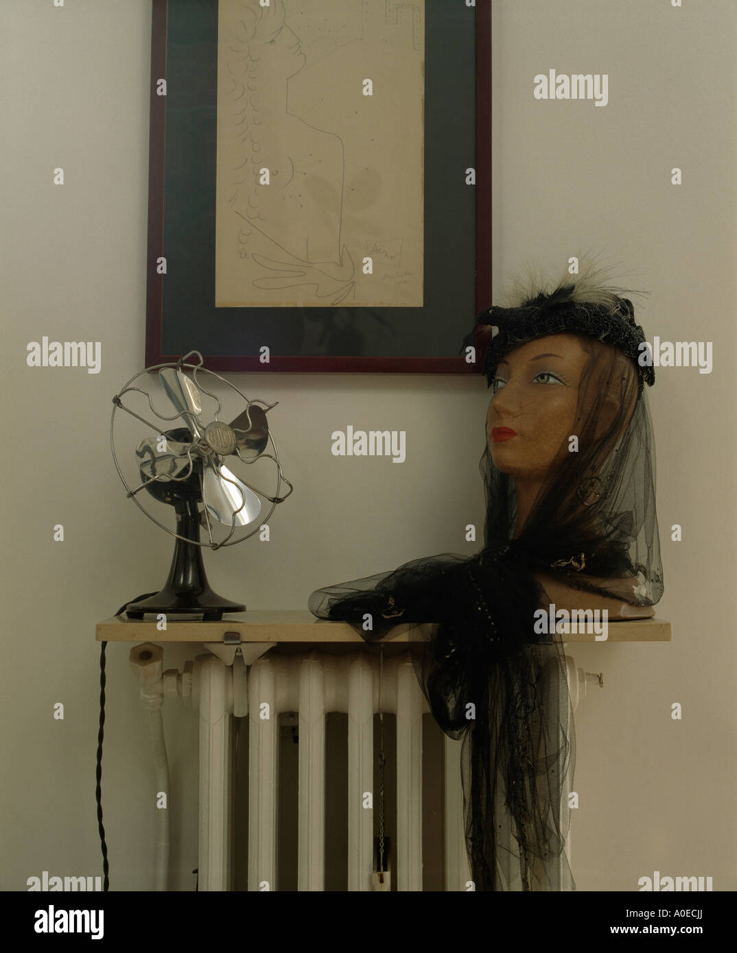 Closeup of electric fan and bust with black veil on shelf above