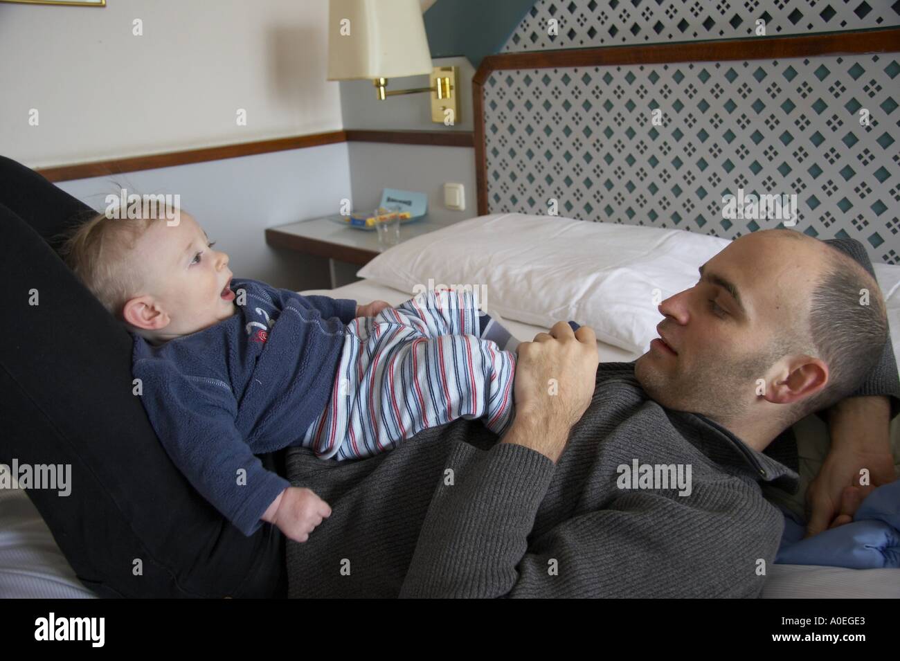 father lying with baby on bed Stock Photo - Alamy