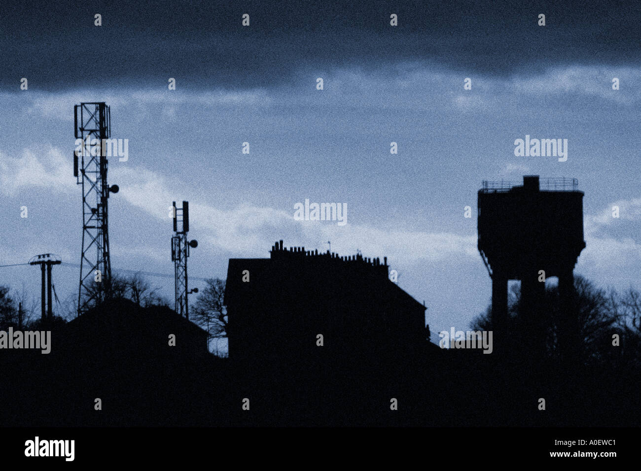 Atmospheric shot of industrial location with houses water tower and mobile phone masts Stock Photo