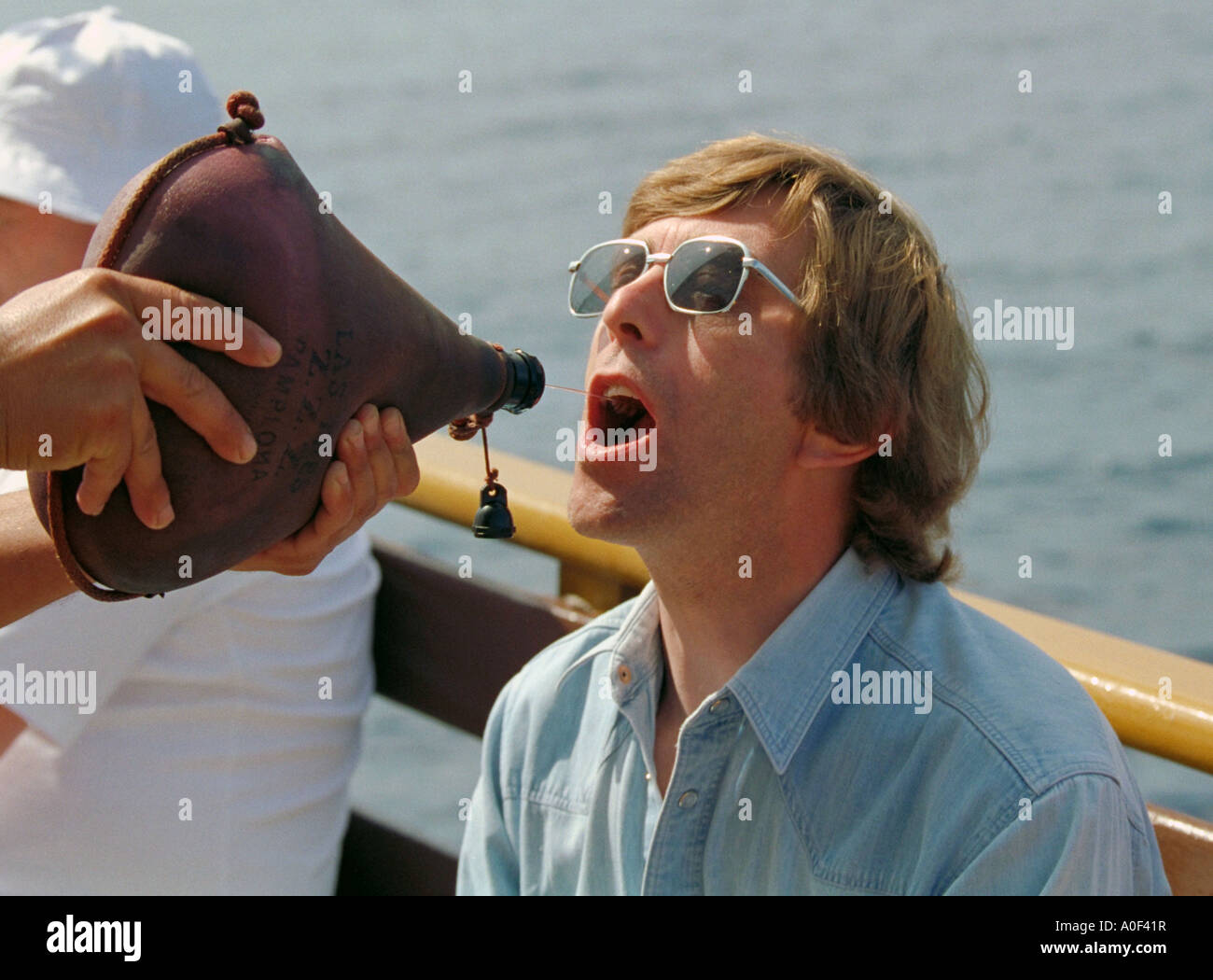Squirting Wine into a Mans Mouth from a Wine Bag on a Tourist Boat Trip Stock Photo