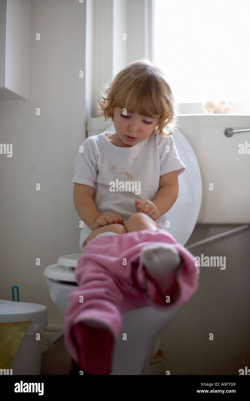 Young girl sitting on toilet Stock Photo - Alamy