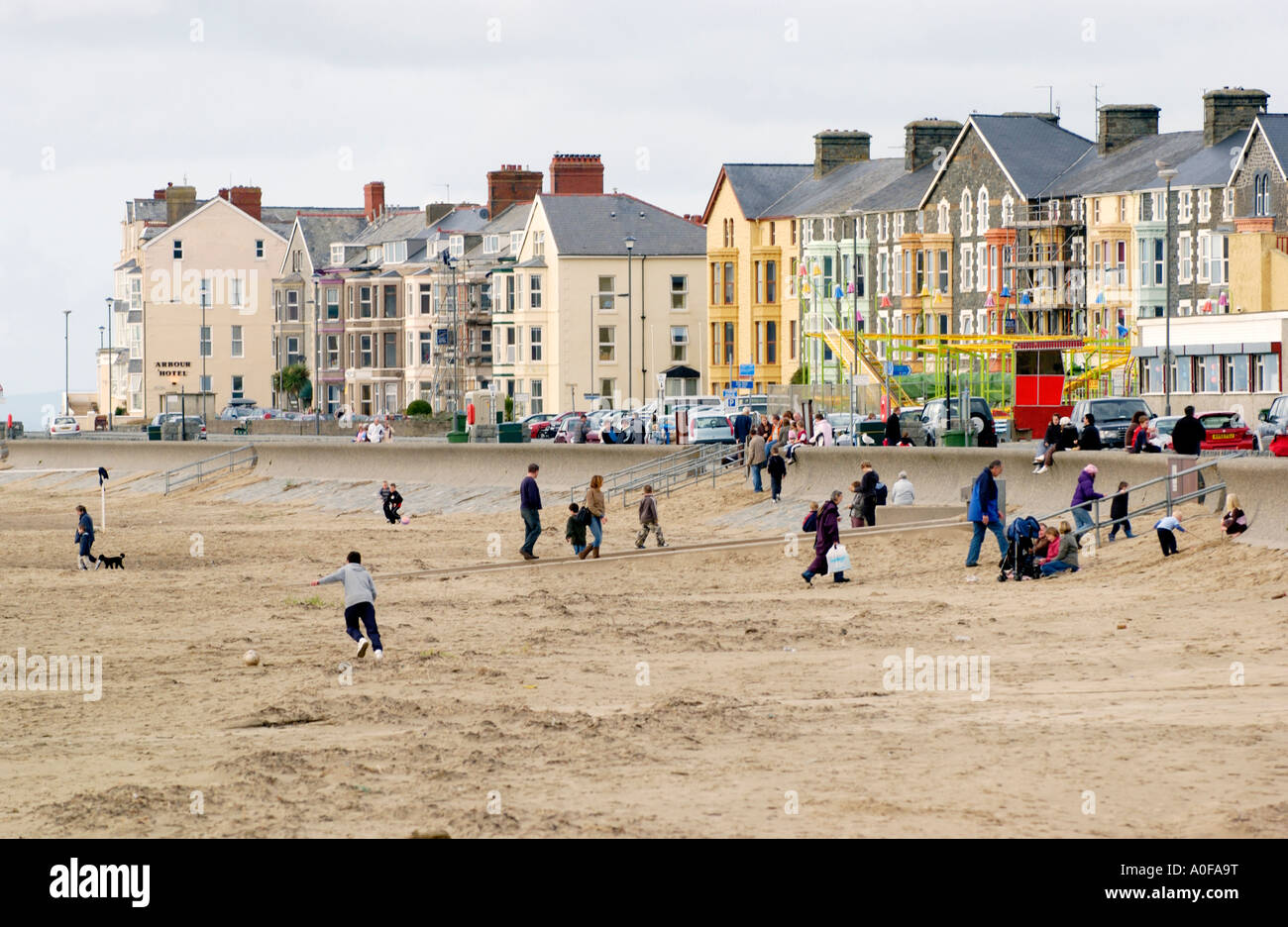 People walk along seafront at Barmouth Gwynedd North Wales UK houses in