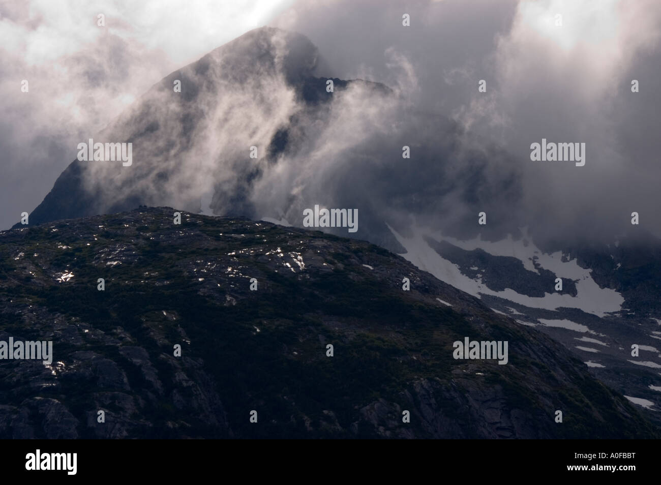 View of a mountain peak shrouded in clouds along the coast of Skagway ...