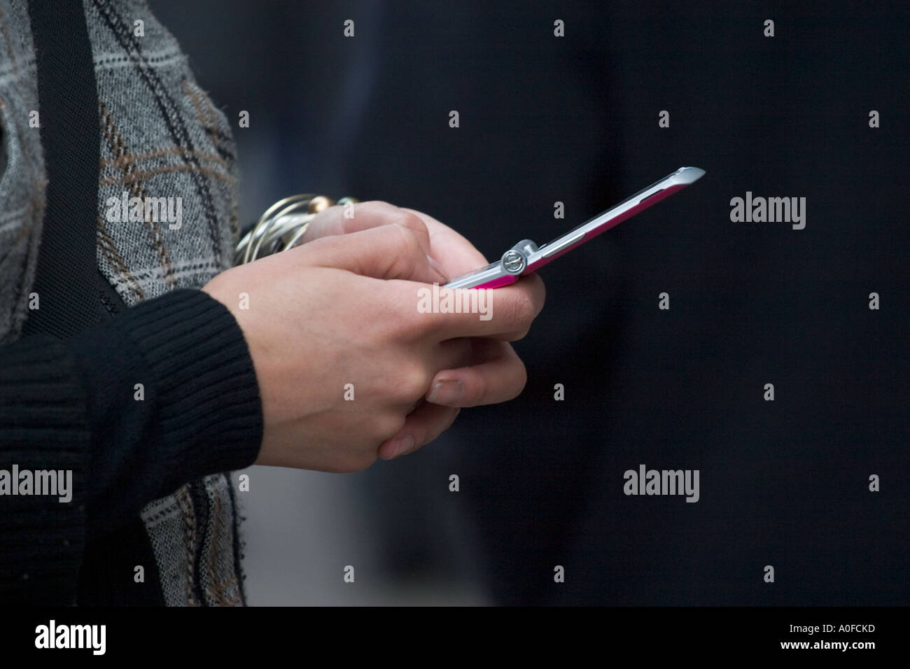 Shopper pauses on Oxford Street to send a text on her mobile phone Stock Photo