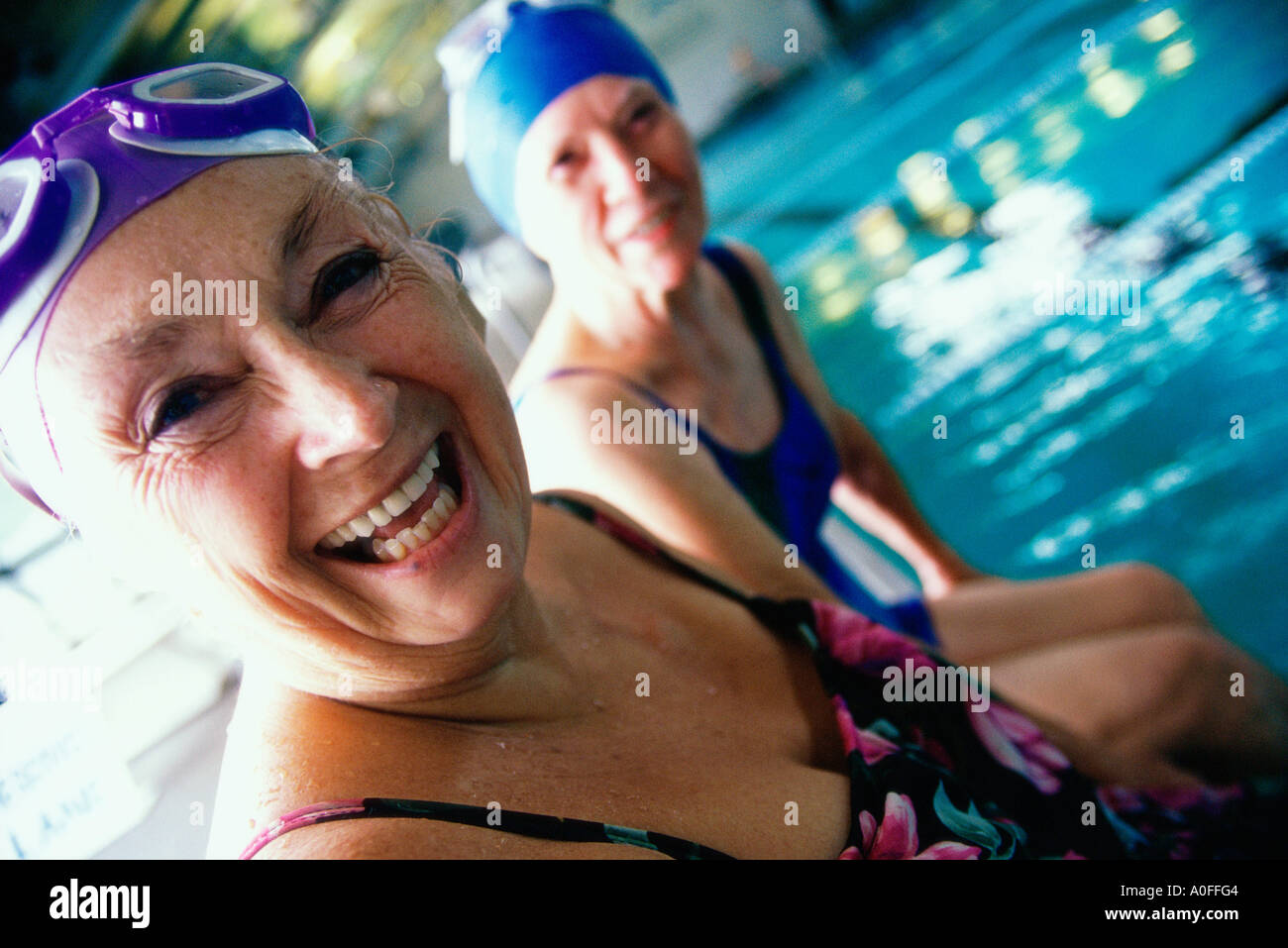 Two women sitting by the side of a swimming pool hi-res stock ...