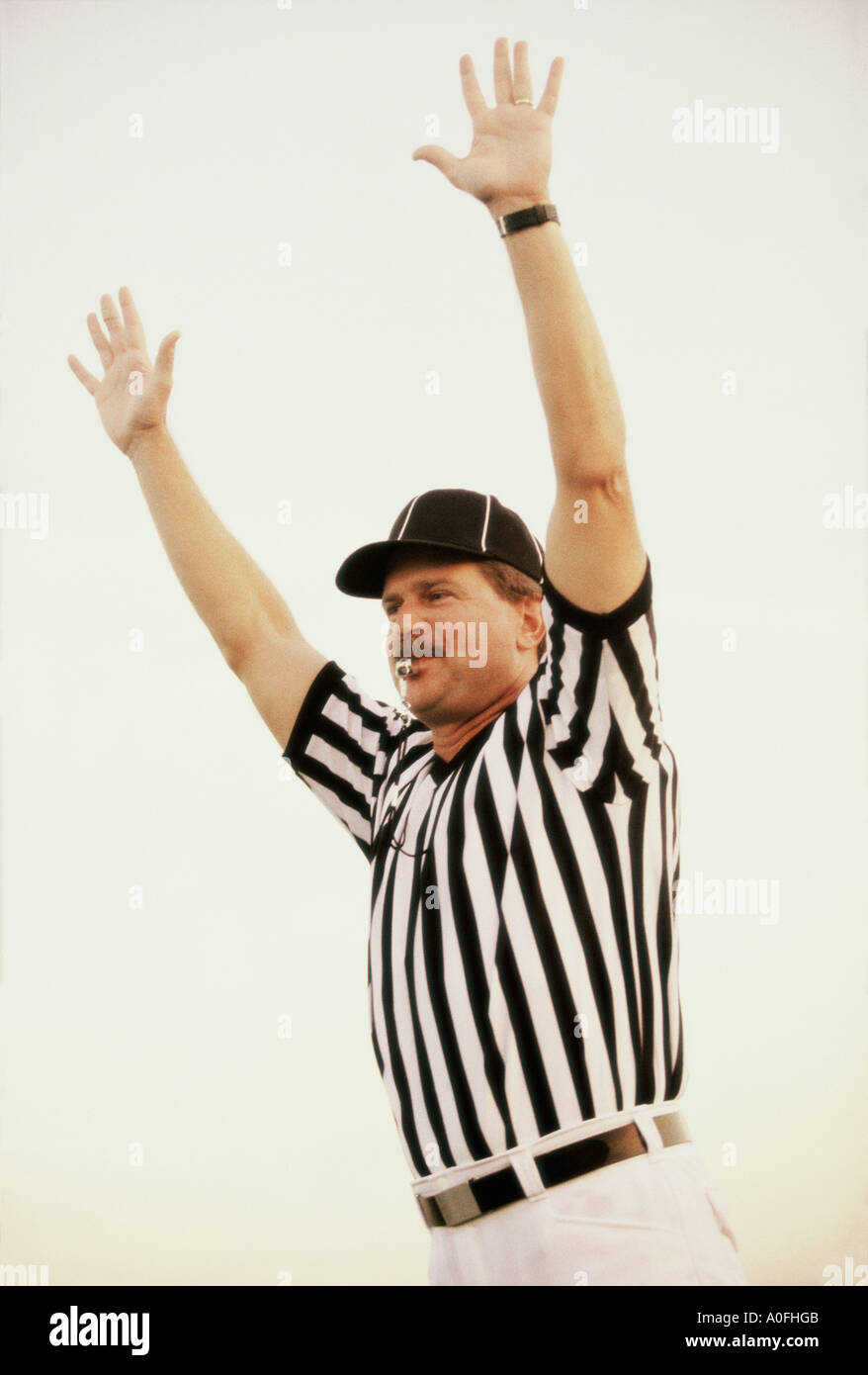 Football referee whistling with his arms raised Stock Photo Alamy
