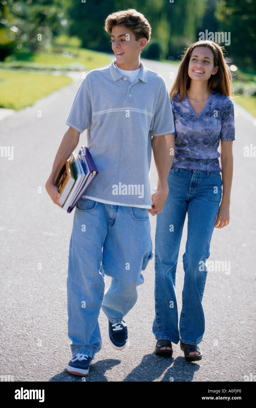 Teenage couple holding hands while walking outdoors Stock Photo - Alamy