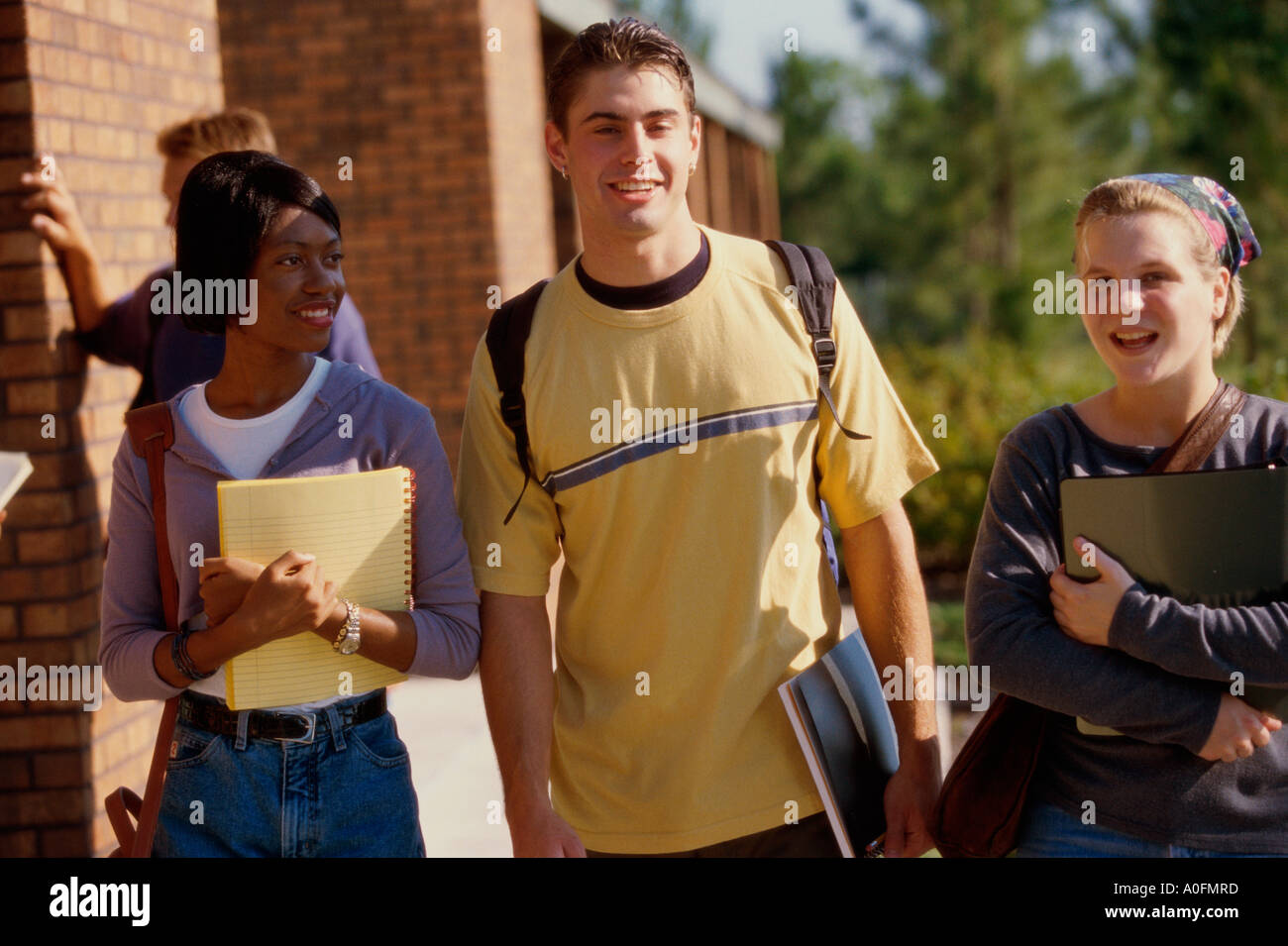Young man walking with two young women Stock Photo - Alamy
