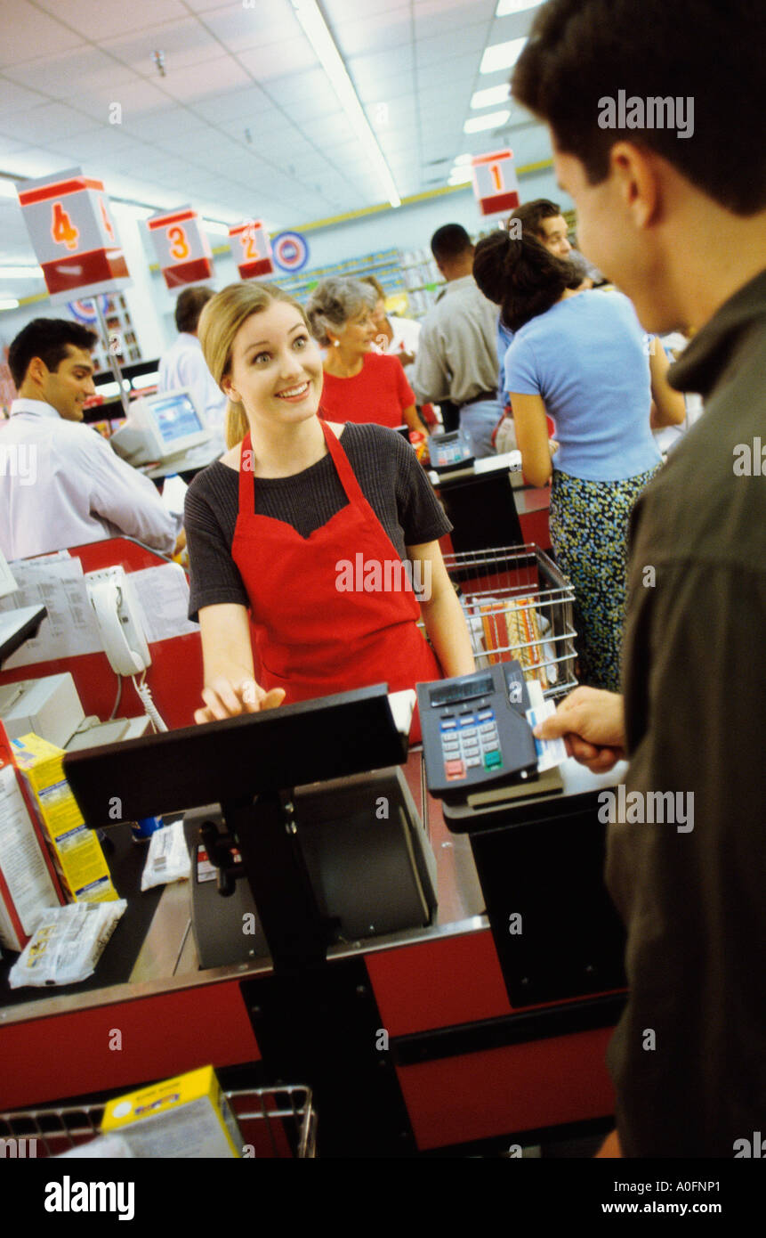 Young man using a credit card machine at a checkout counter in a supermarket Stock Photo