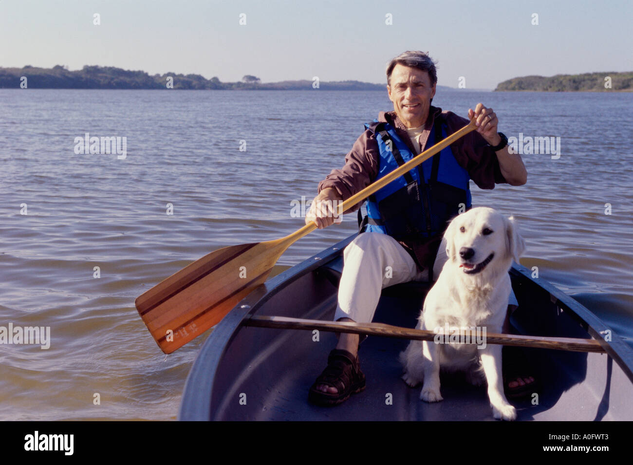 Portrait of a mid adult man sitting in a row boat with his dog Stock Photo