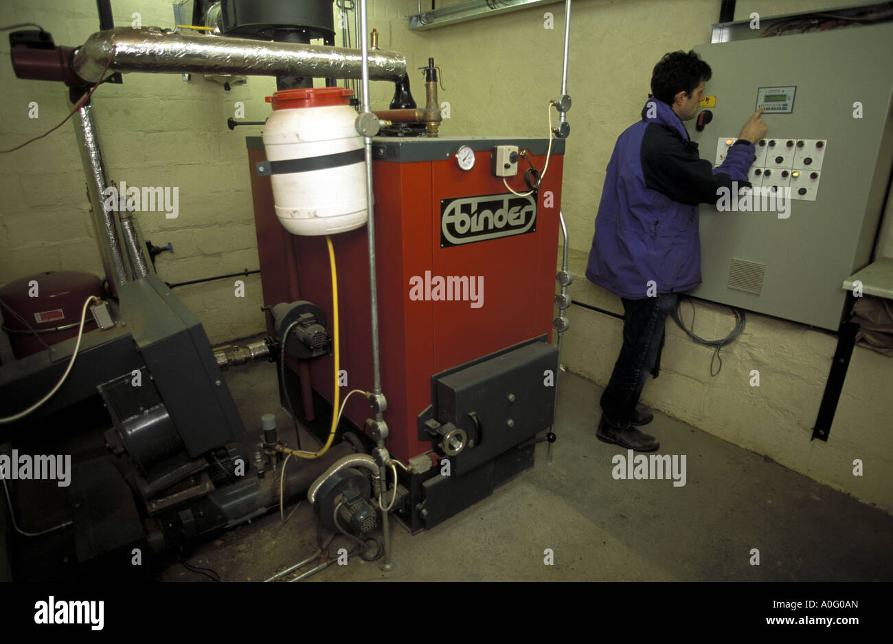 Andrew Sheridan of the Energy Trust adjusts 93 KW Woodchip boiler enough to heat six semi detached houses Oakham Leicestershire Stock Photo