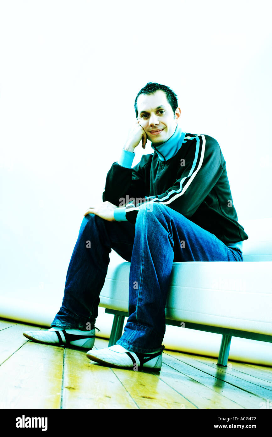 Young man sitting on a sofa and looking down at the camera Stock Photo