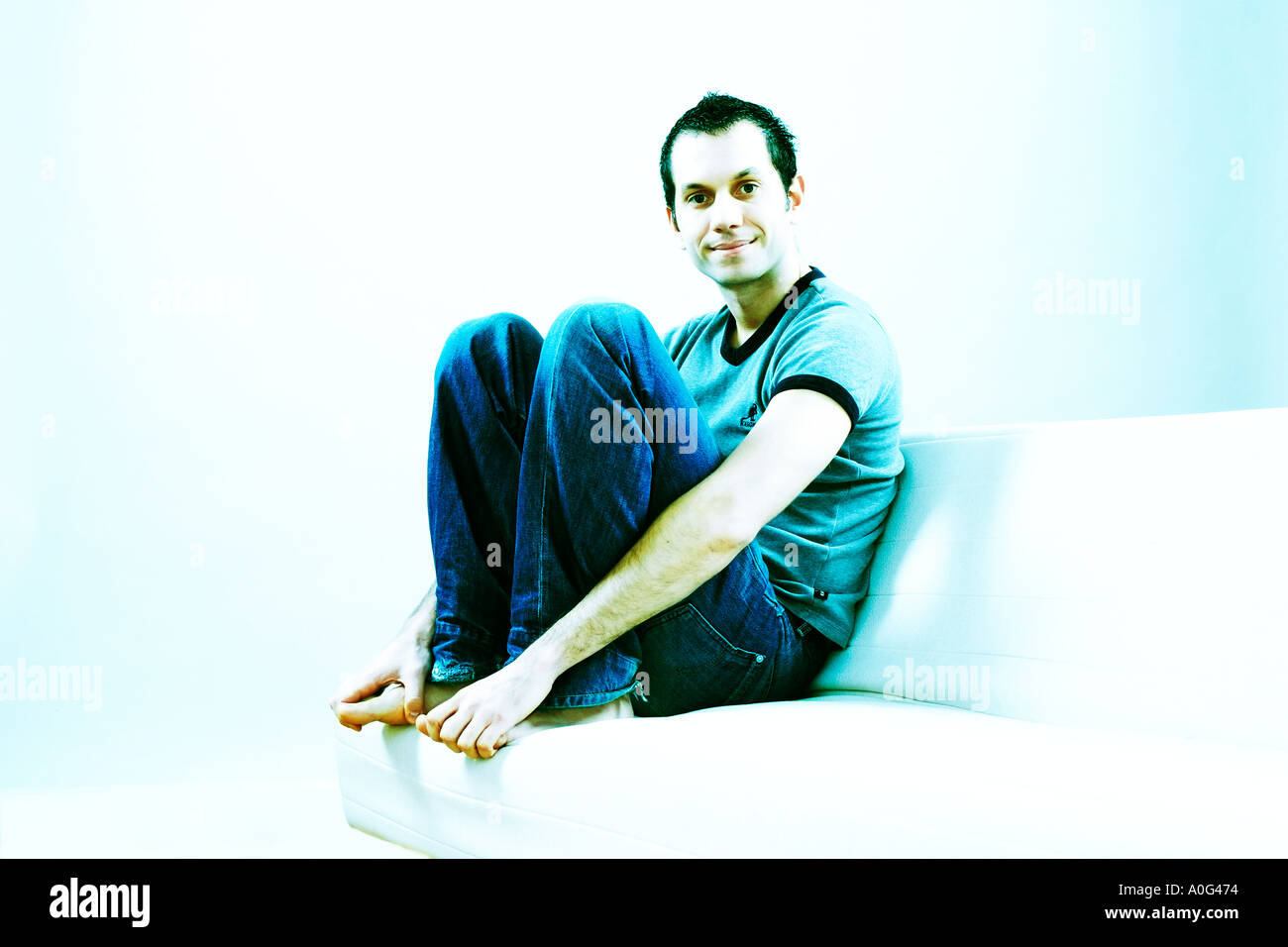 Young man sitting on a sofa and looking at the camera Stock Photo