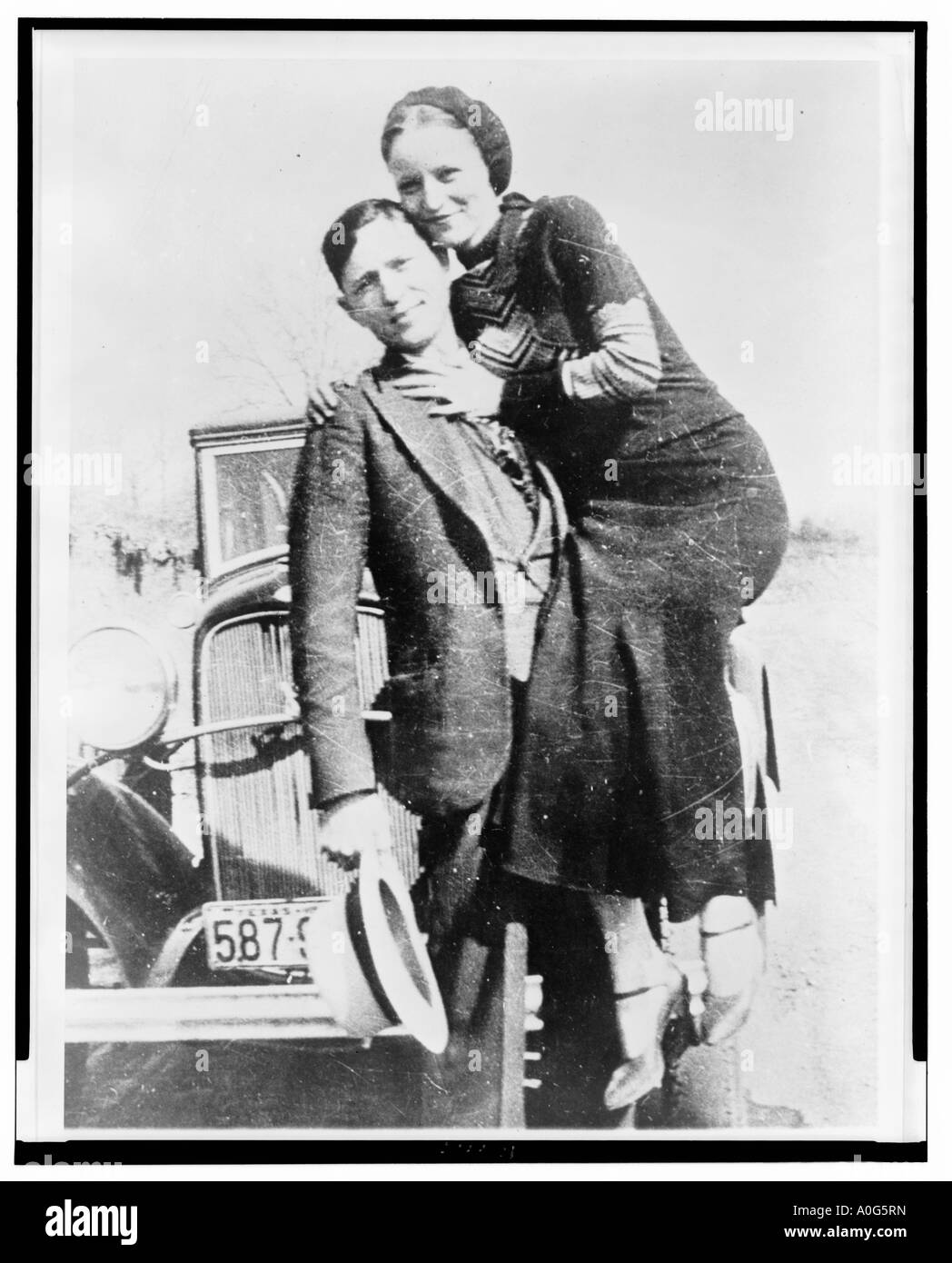 Clyde Barrow holding Bonnie Parker on one arm facing front in front of automobile Stock Photo