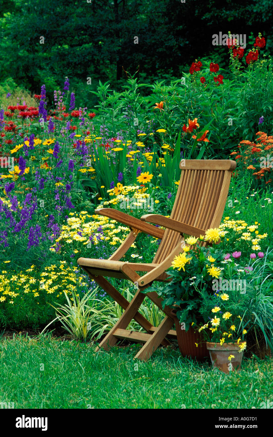 Wooden chair in colorful flower garden with annuals and perennials