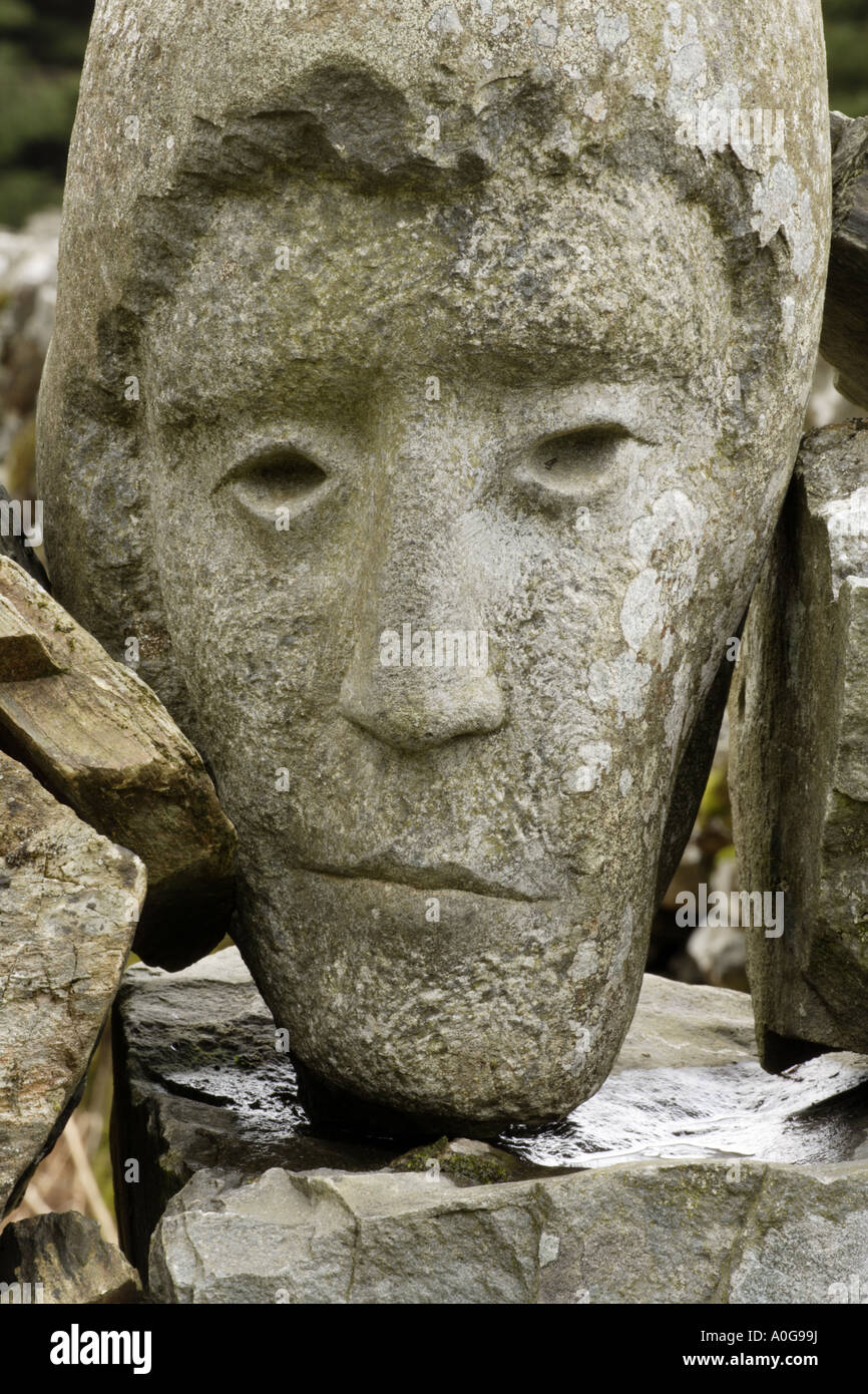 Sculpture of a face carved in stone in a dry stane dyke by Matt Baker