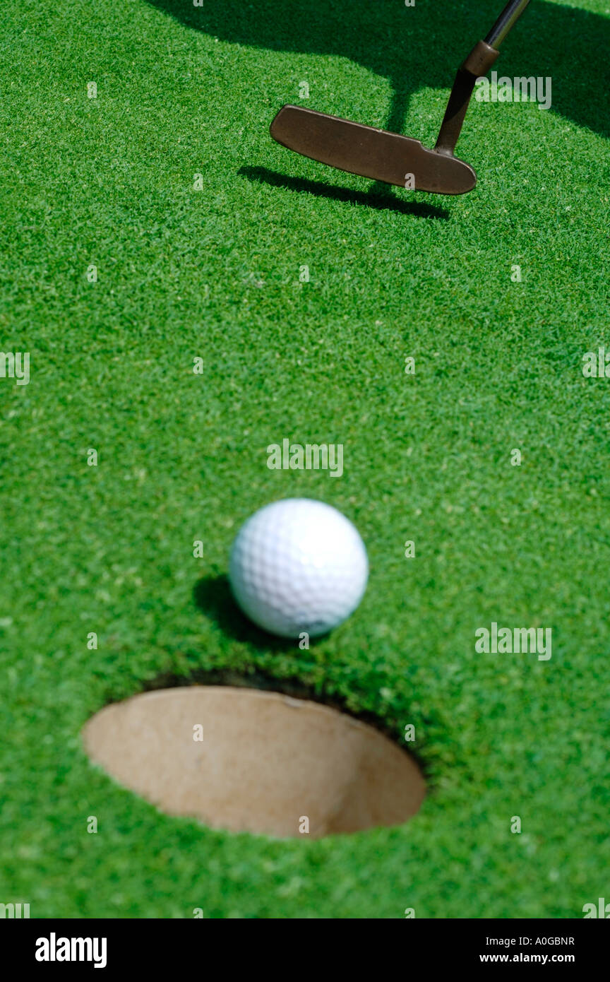 Golfer putting a ball with hole in foreground Stock Photo