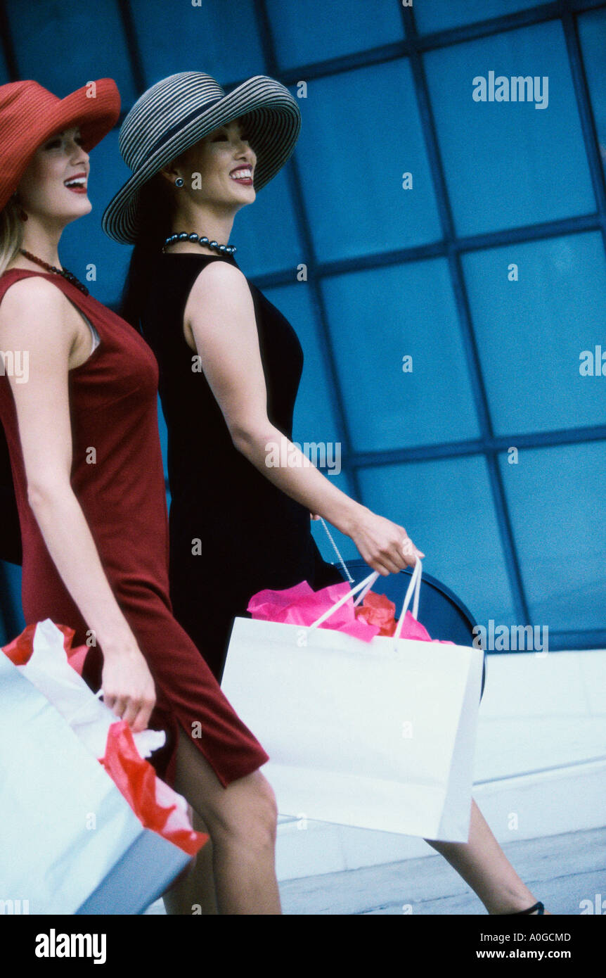 Side profile of two young women walking with shopping bags Stock Photo ...