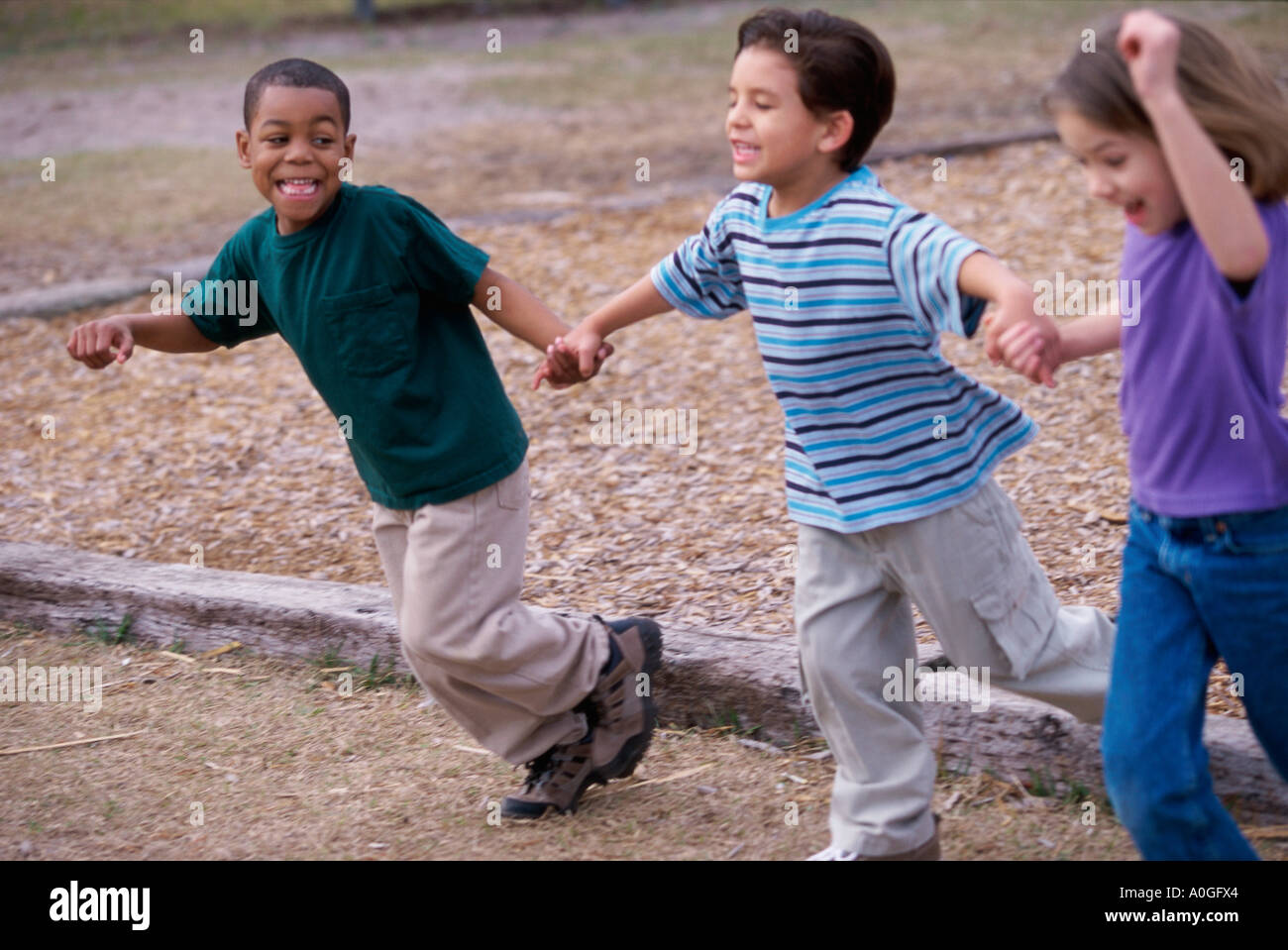 Two boys and a girl running holding hands Stock Photo - Alamy