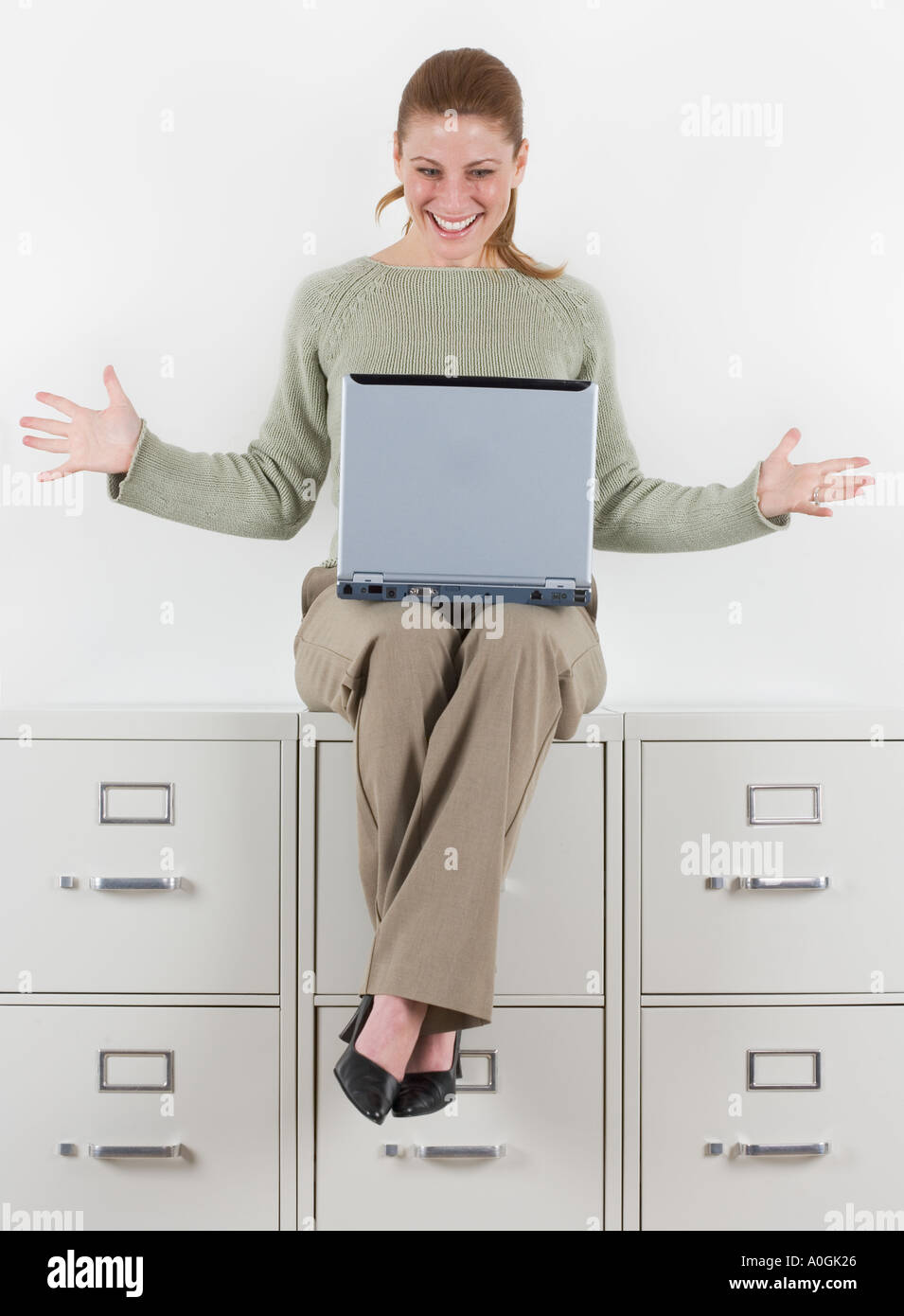 Woman with laptop atop file cabinets Stock Photo