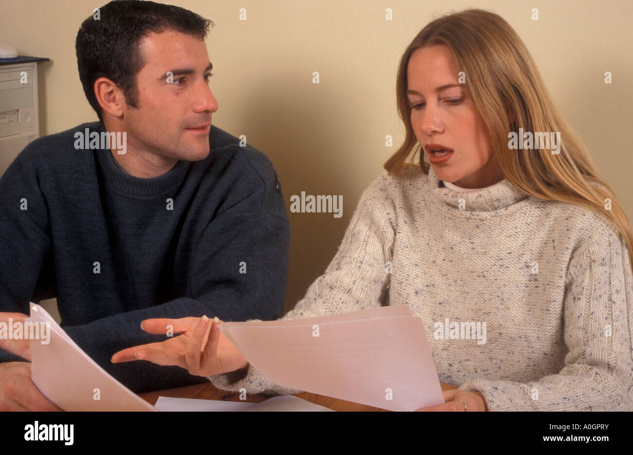 young couple sitting at table having discussion over papers Stock Photo
