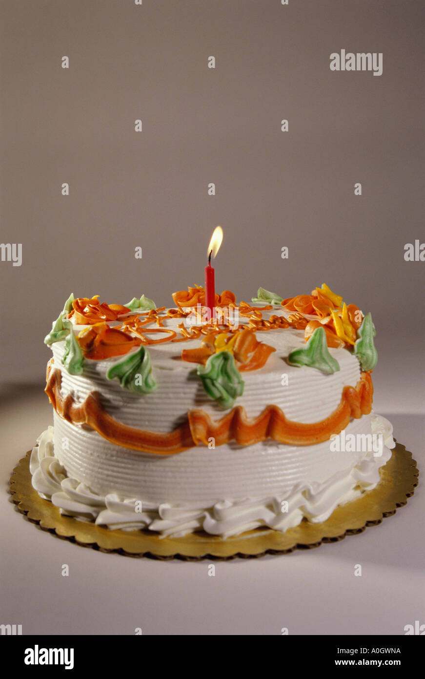 Decorated birthday cake with a lit candle Stock Photo - Alamy