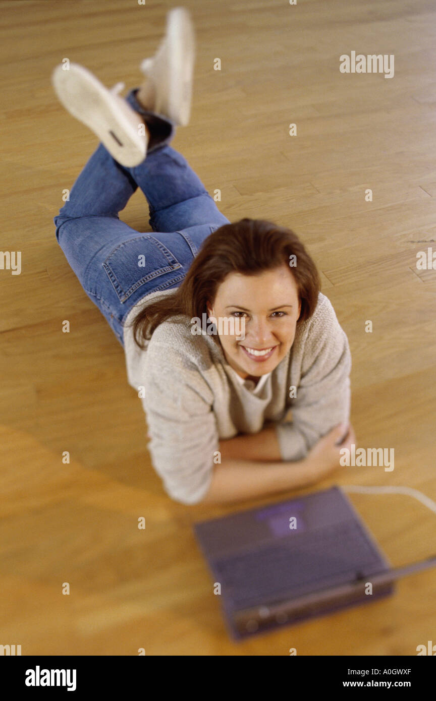 Portrait of a mid adult woman lying on the floor with a laptop Stock ...
