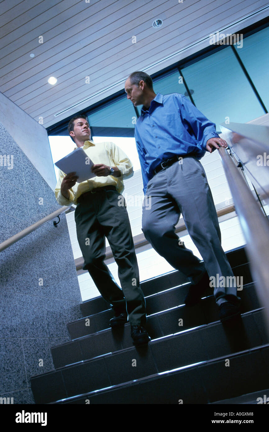 Low angle view of two businessmen walking down stairs Stock Photo - Alamy