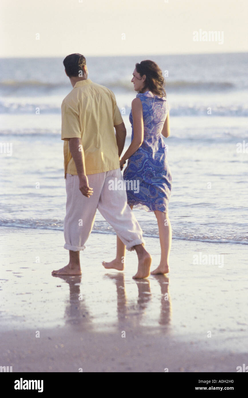 Rear view of a young couple walking on the beach Stock Photo - Alamy