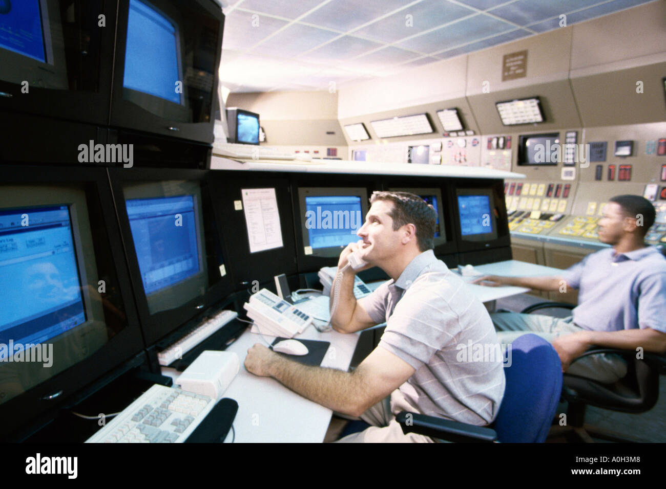 Two mid adult men sitting in a electric power control room Stock Photo