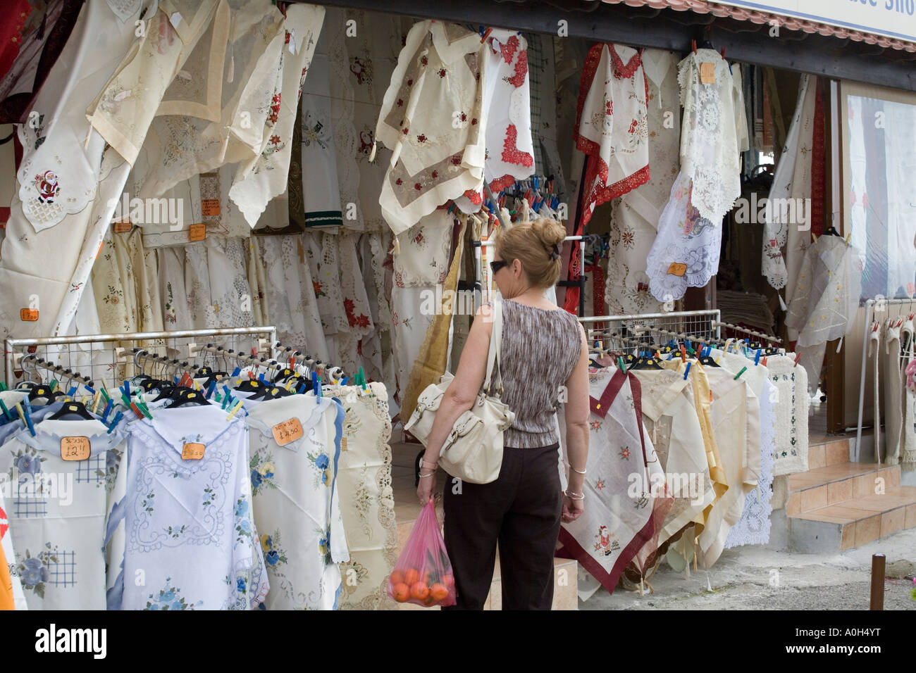 A MIDDLE AGED TOURIST LOOKING AT LOCAL LINEN IN PAPHOS CYPRUS Stock Photo