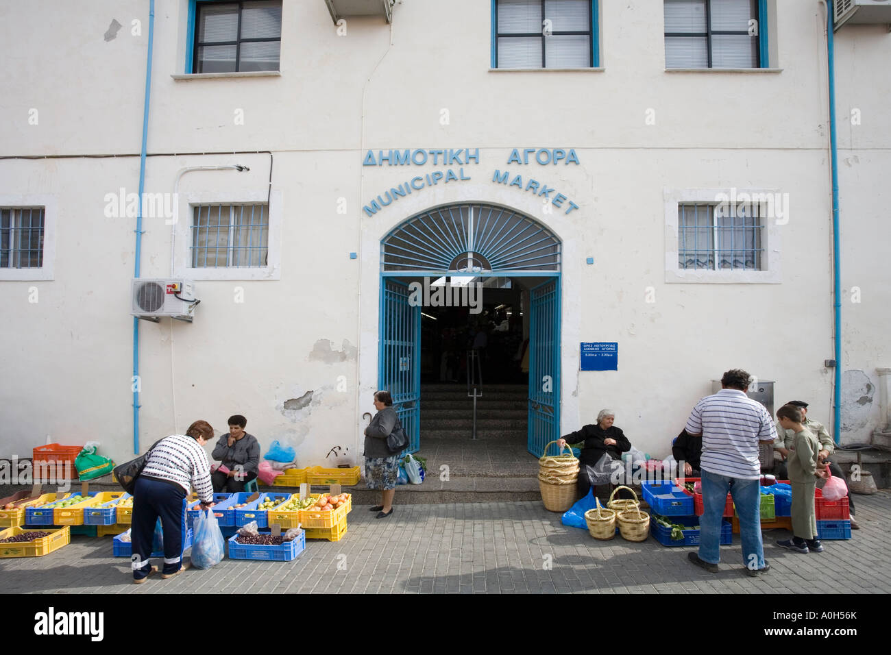 THE ENTRANCE TO THE INDOOR MUNICIPAL MARKET IN PAPHOS, CYPRUS, WITH MARKET SELLERS FROM THE OUTDOOR PRODUCE MARKET EITHER SIDE Stock Photo