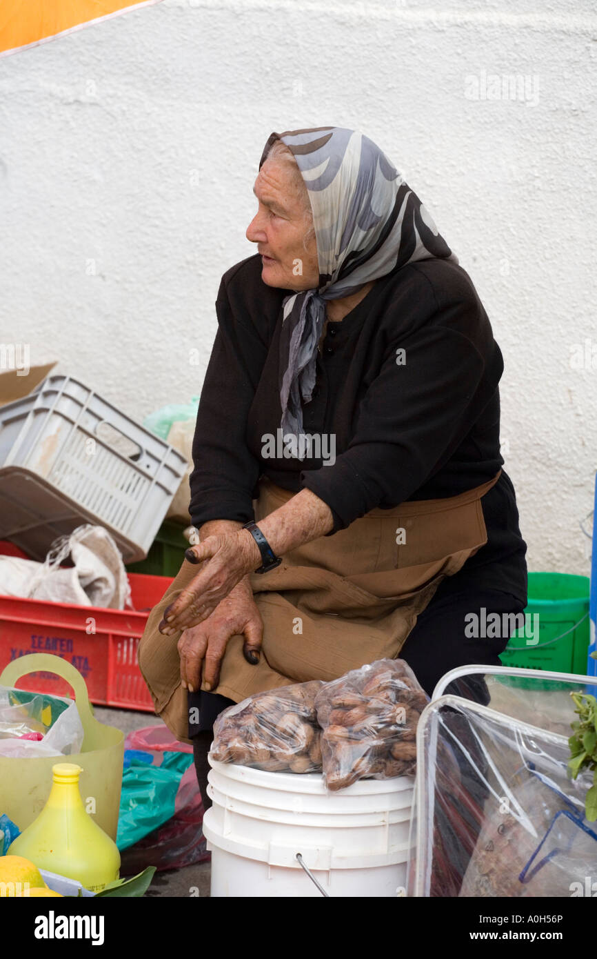 A LOCAL WOMAN IN TRADITIONAL BLACK, AT THE MARKET IN THE TOWN CENTRE OF OLD PAPHOS, CYPRUS, SELLING NUTS Stock Photo