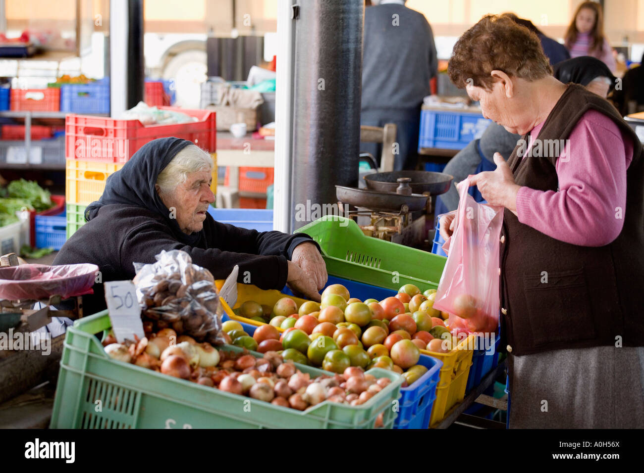 A LOCAL WOMAN IN TRADITIONAL BLACK, AT THE MARKET IN THE TOWN CENTRE OF OLD PAPHOS, CYPRUS WITH A CUSTOMER Stock Photo