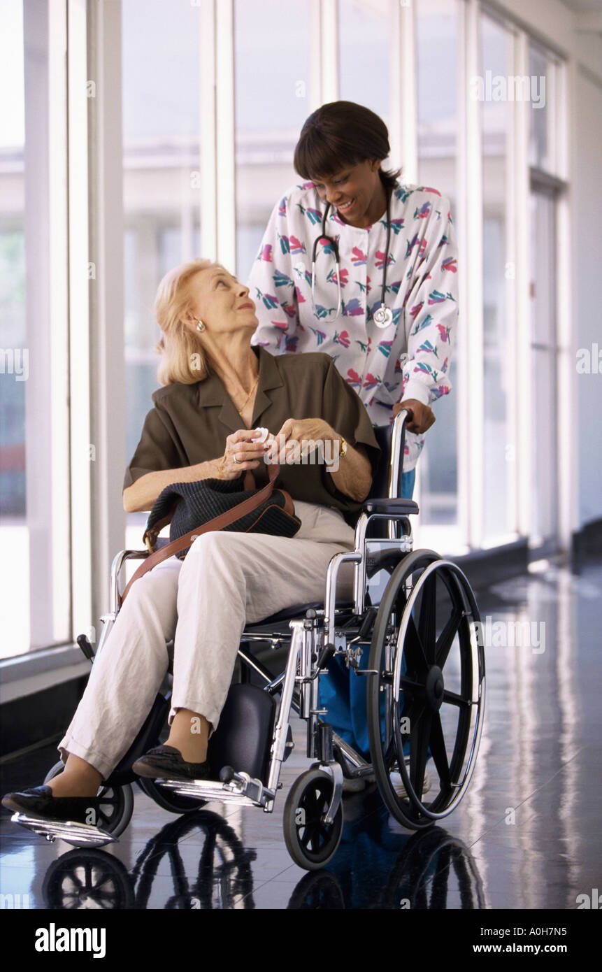 Female nurse pushing a female patient in a wheelchair Stock Photo - Alamy