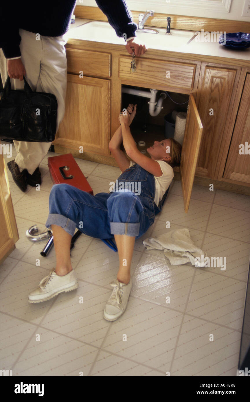 Young woman repairing the plumbing under a kitchen sink Stock Photo - Alamy