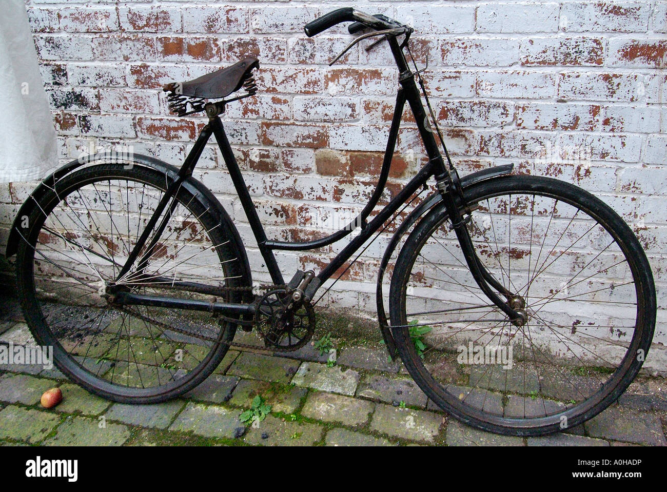 bicycle bike women woman antique ladies lady old bone shaker black parked  left white washed wall cobble spoke wheel Stock Photo - Alamy