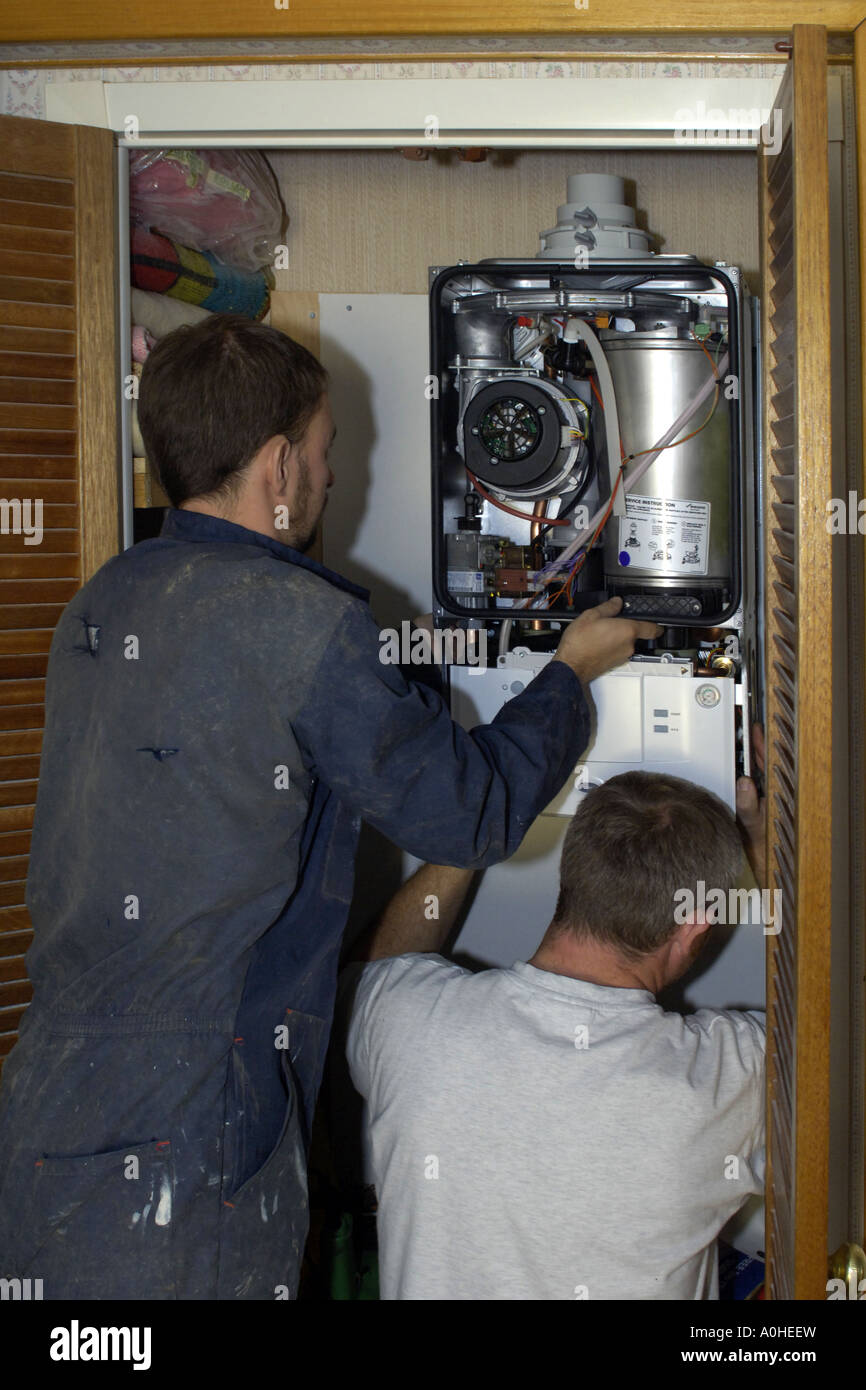 Two adult male workers installing a new Combi boiler into a house. Stock Photo