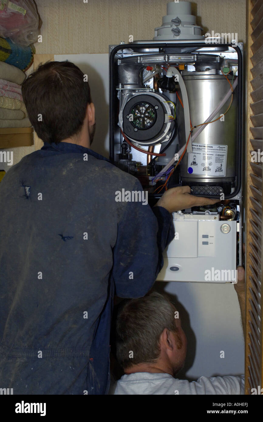 Two adult male workers installing a new Combi boiler into a house Stock