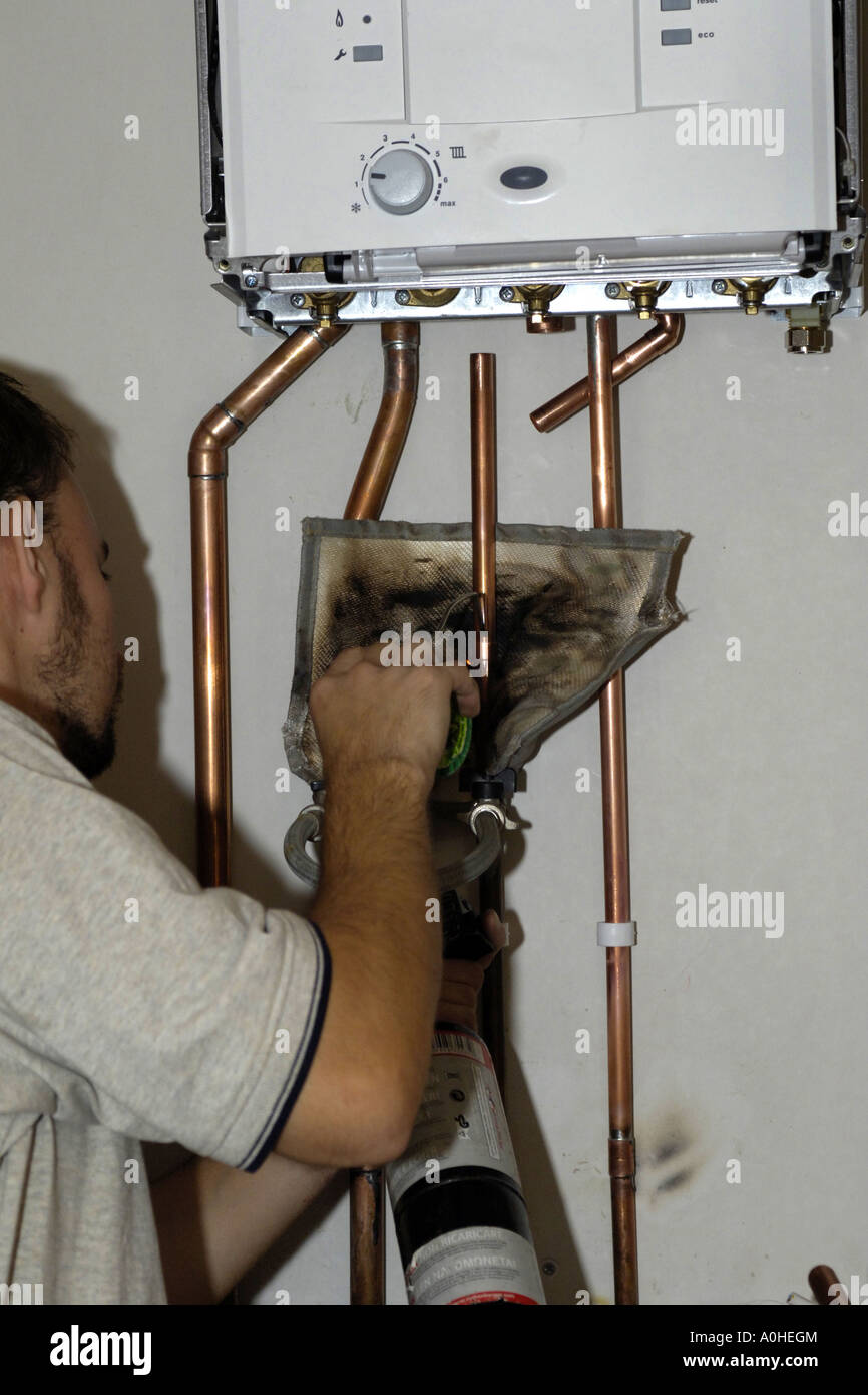 Adult male worker installing new pipework using a gas burner to solder the joints on a new central heating boiler Stock Photo